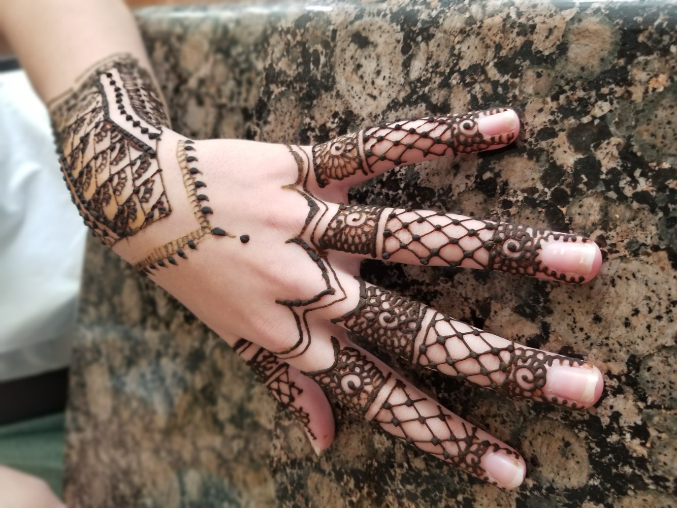 Detailed lace-style henna across the hand and fingers